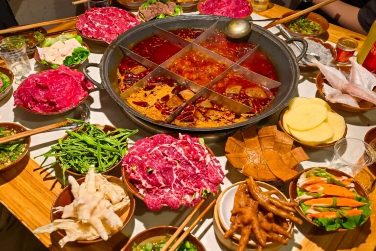 Hot pot pedas khas Chongqing dengan daging dan sayuran segar di atas meja.