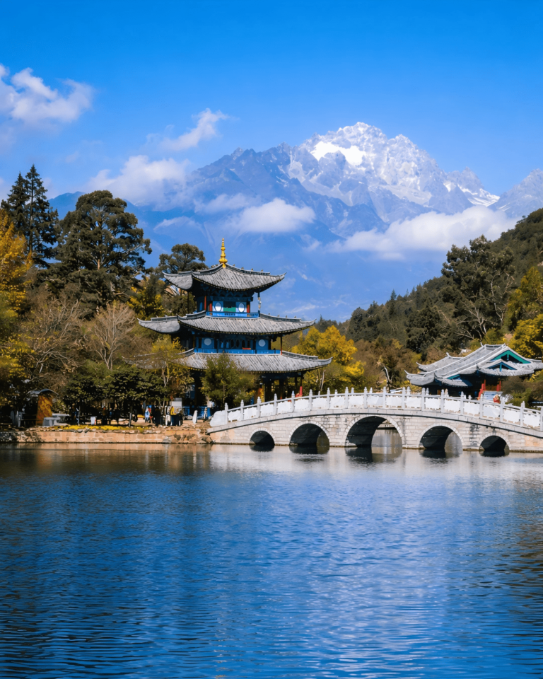 Stone bridge and pavilion at Black Dragon Pool with Jade Dragon Snow Mountain in the background.