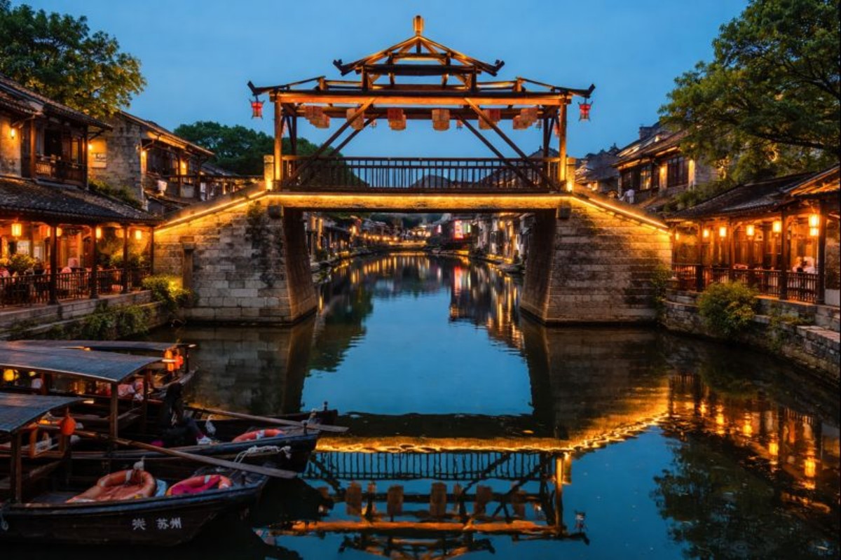 Lit bridge and canal with boats in a historic Chinese town
