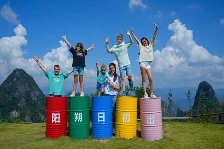 Family posing on colorful barrels with mountain scenery and blue sky during a Guilin outdoor tour in China