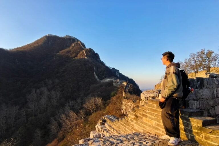 Traveler standing on the Great Wall overlooking mountain peaks during golden hour in China