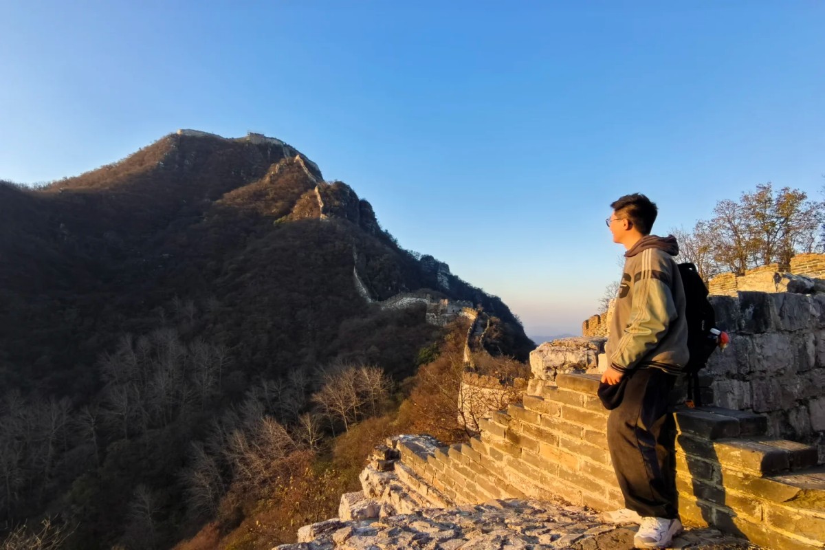 Traveler standing on the Great Wall overlooking mountain peaks during golden hour in China