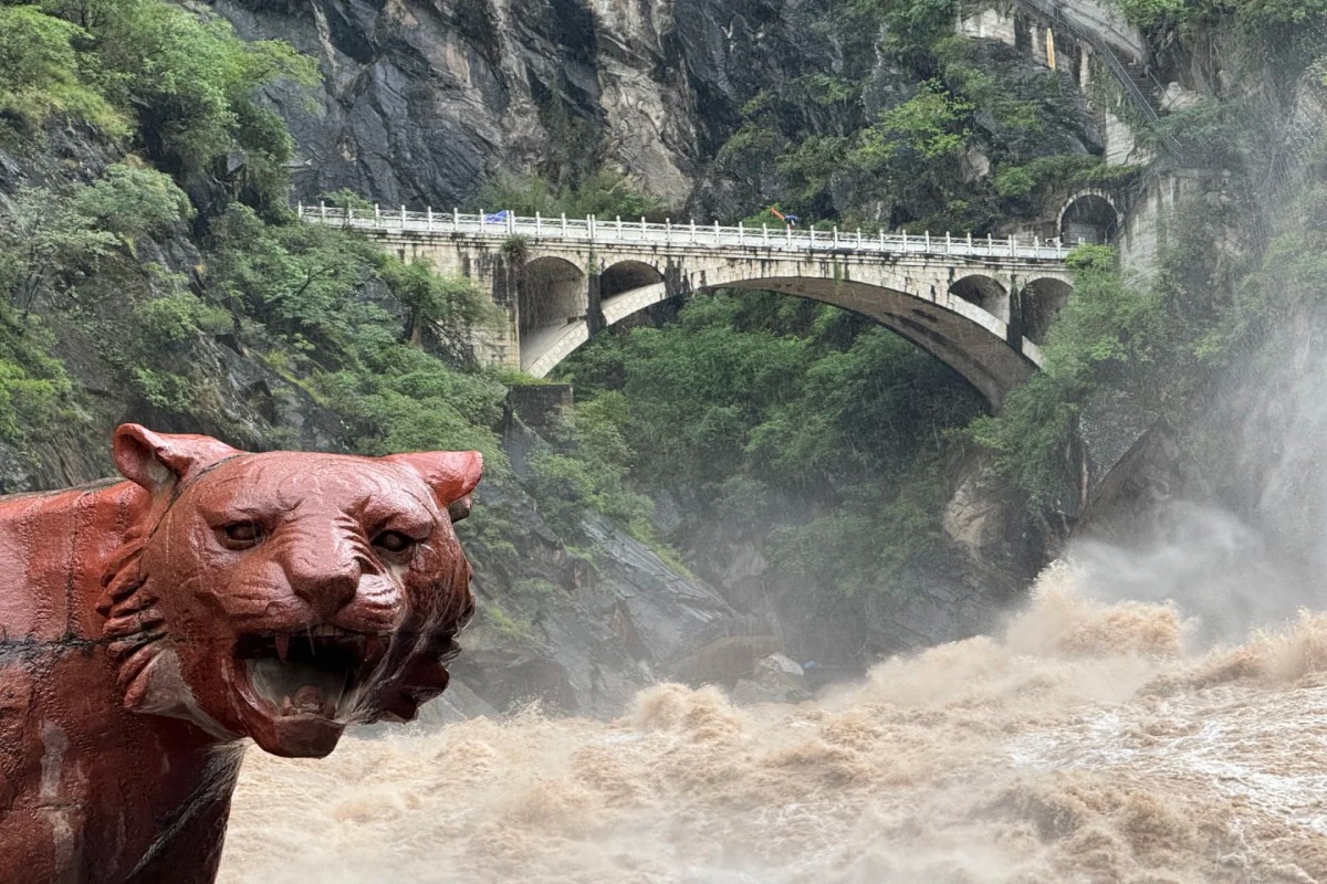 Raging river at gorge with stone bridge and tiger statue in foreground