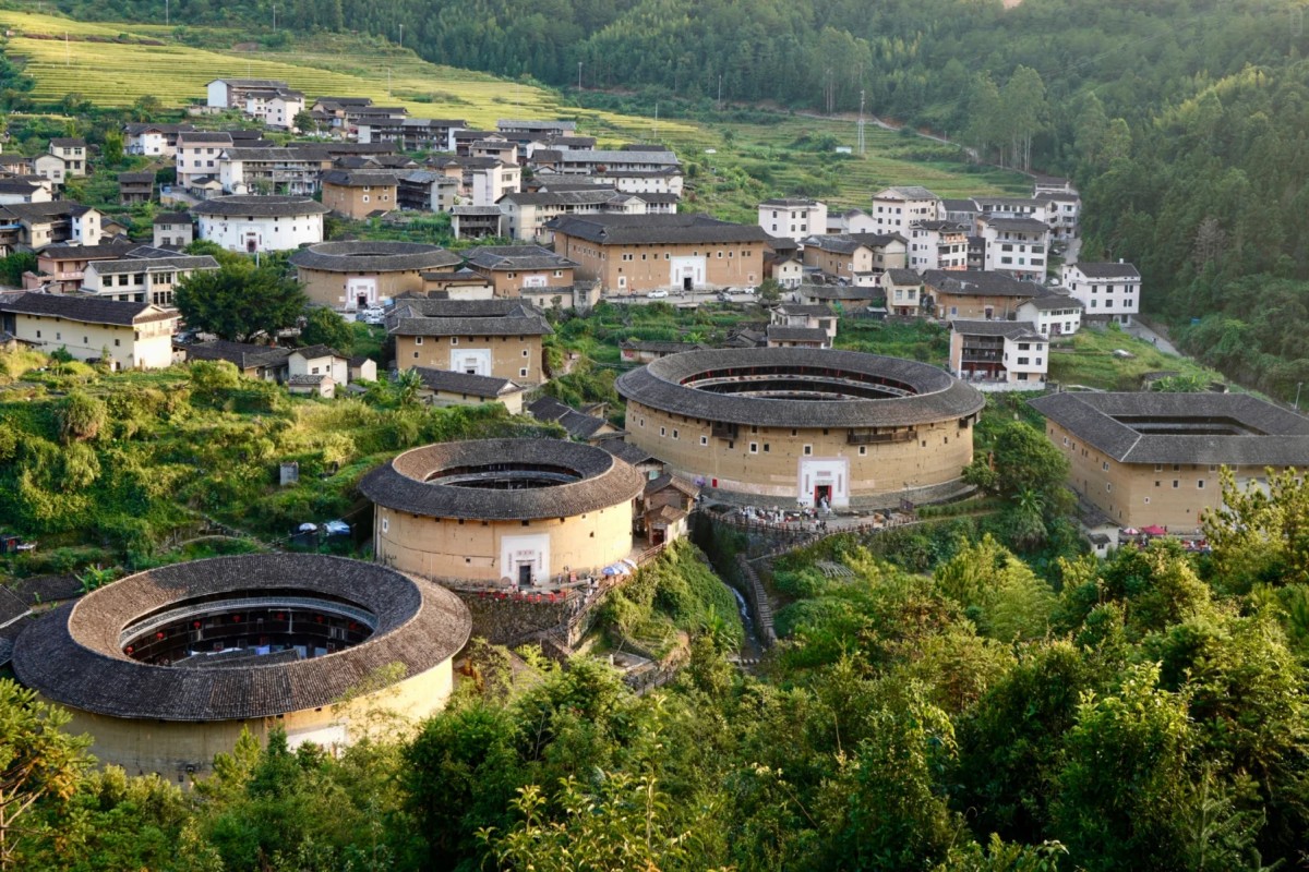 Traditional round tulou buildings surrounded by village and green hills