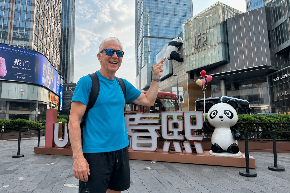 Tourist posing beside panda sculpture at Chengdu IFS shopping district.