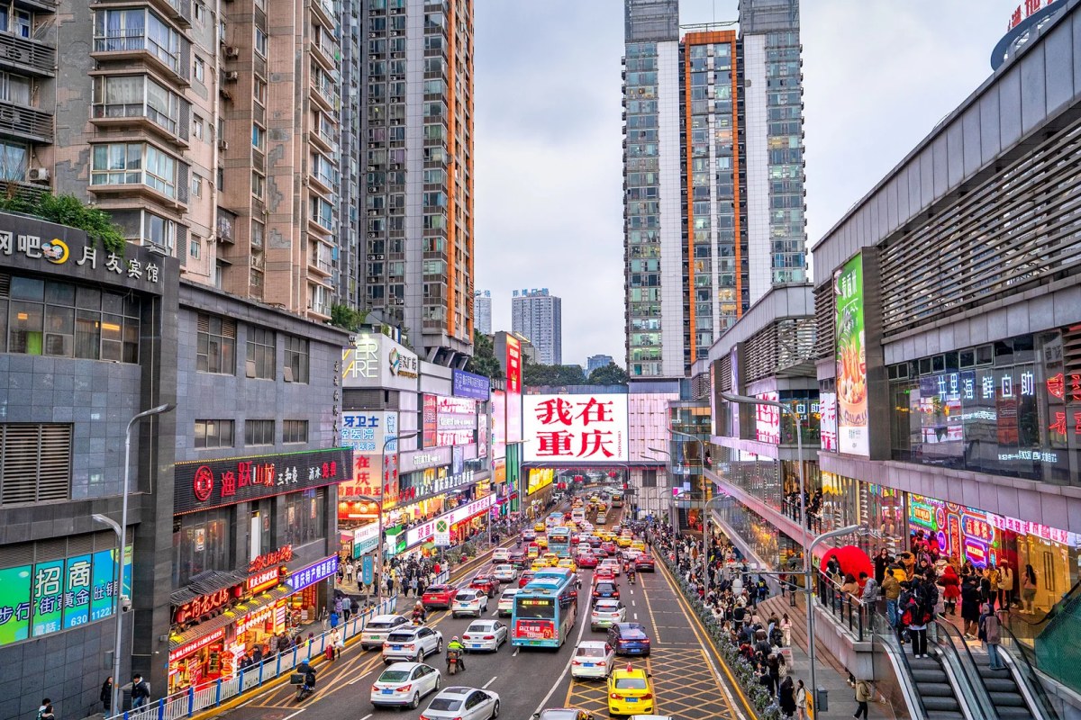 Busy Chongqing shopping street with bright billboards, modern skyscrapers, and lively traffic in the city center.