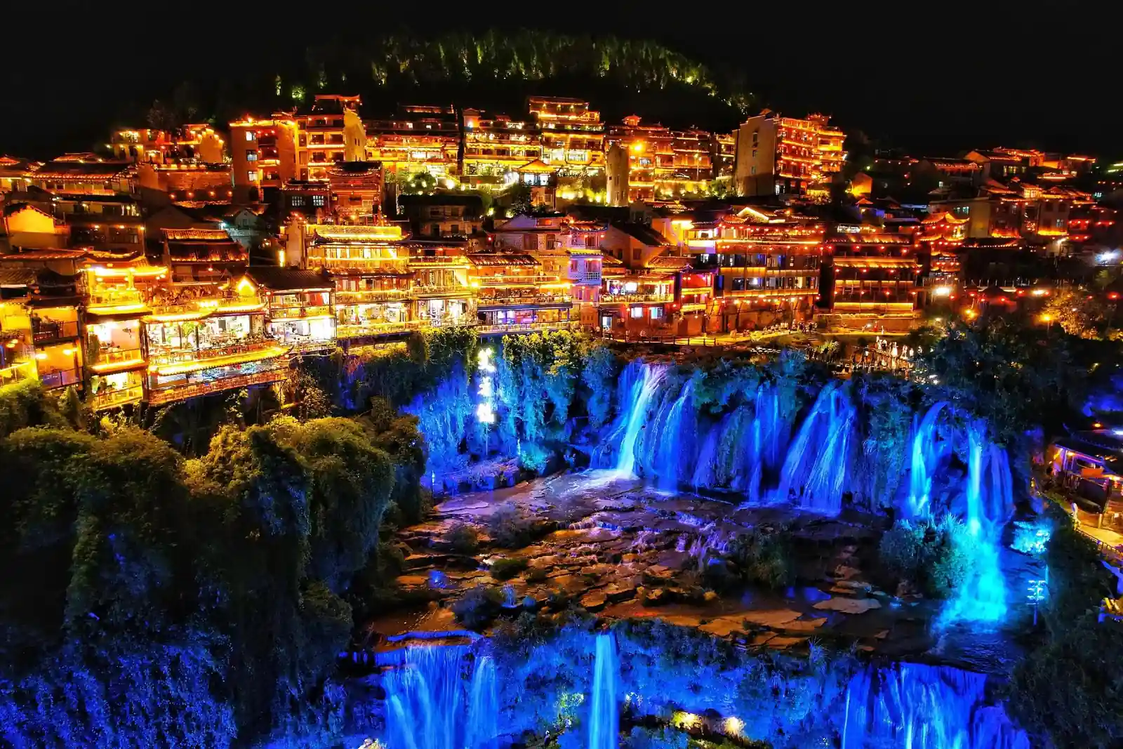 Waterfall and illuminated buildings in Furong Ancient Town