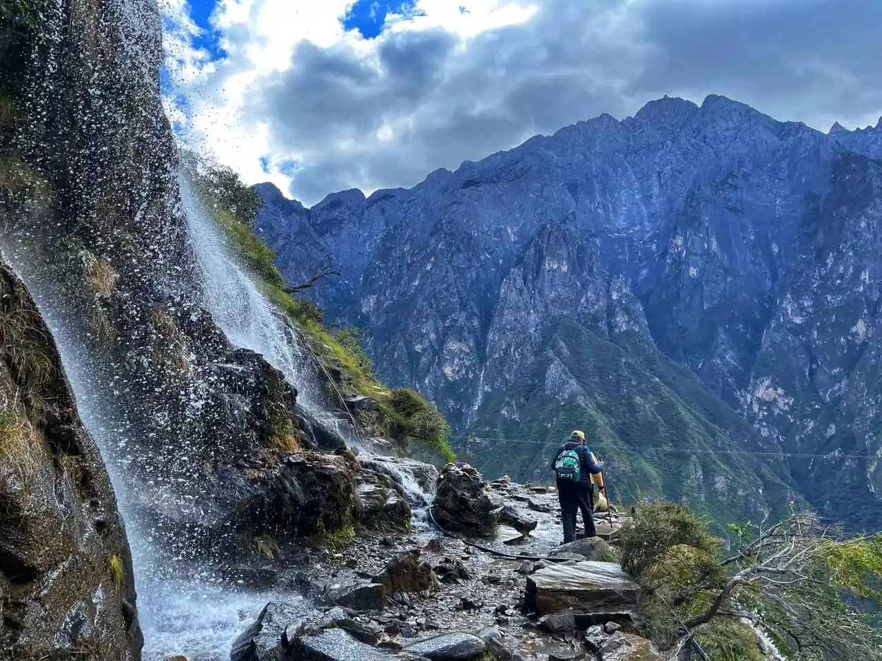 Hiker beside a waterfall on a mountain trail in Tiger Leaping Gorge, Yunnan