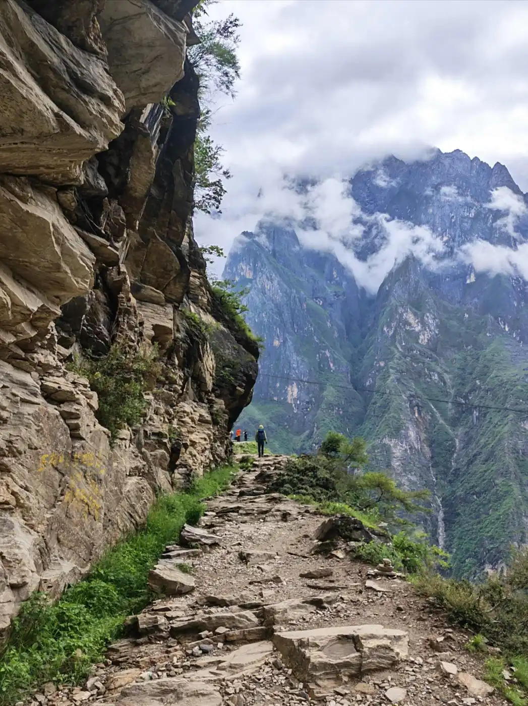 Rocky hiking trail beneath steep mountain cliffs in Tiger Leaping Gorge, Yunnan
