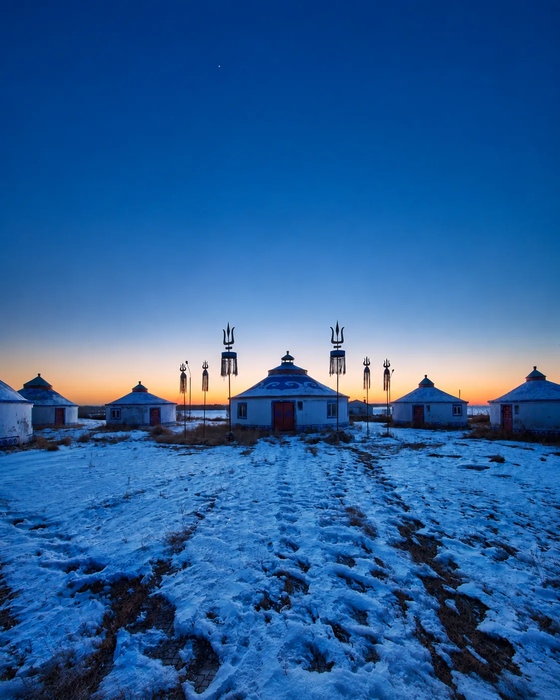 Snow-covered Mongolian yurts on an Inner Mongolia grassland at twilight