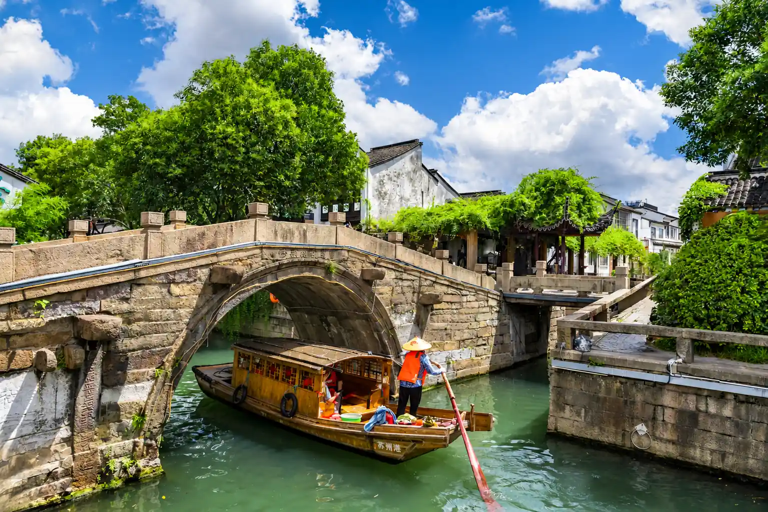 Traditional Boat Passing Under a Stone Bridge in Suzhou