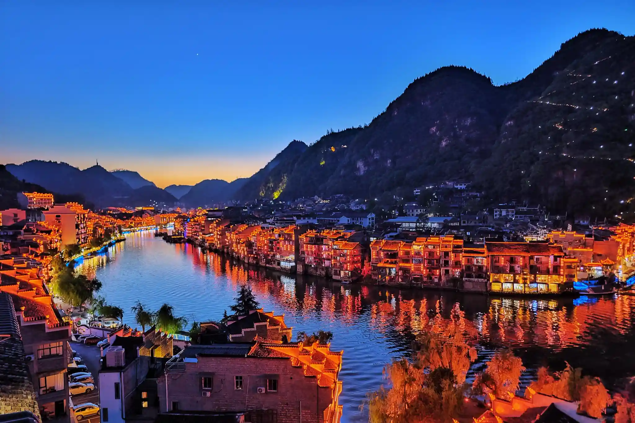 Zhenyuan Ancient Town illuminated at night beside the Wuyang River